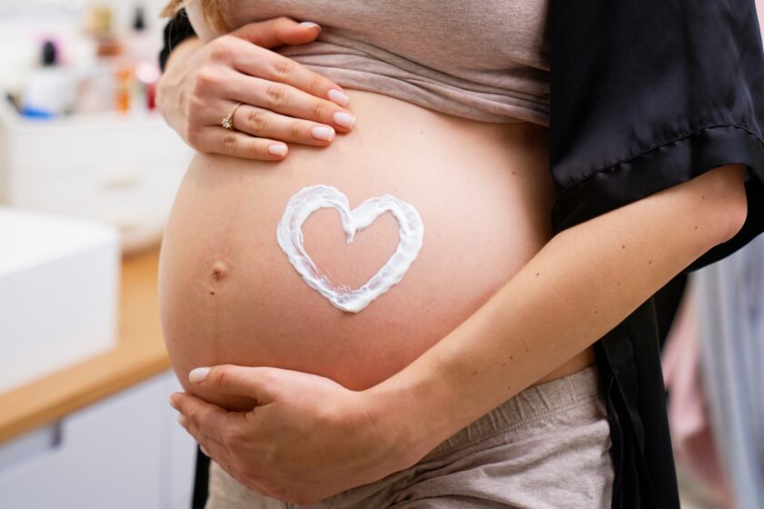 Zdjęcie kobiety w ciążu, która ma namalowane kremem serce na brzuchu