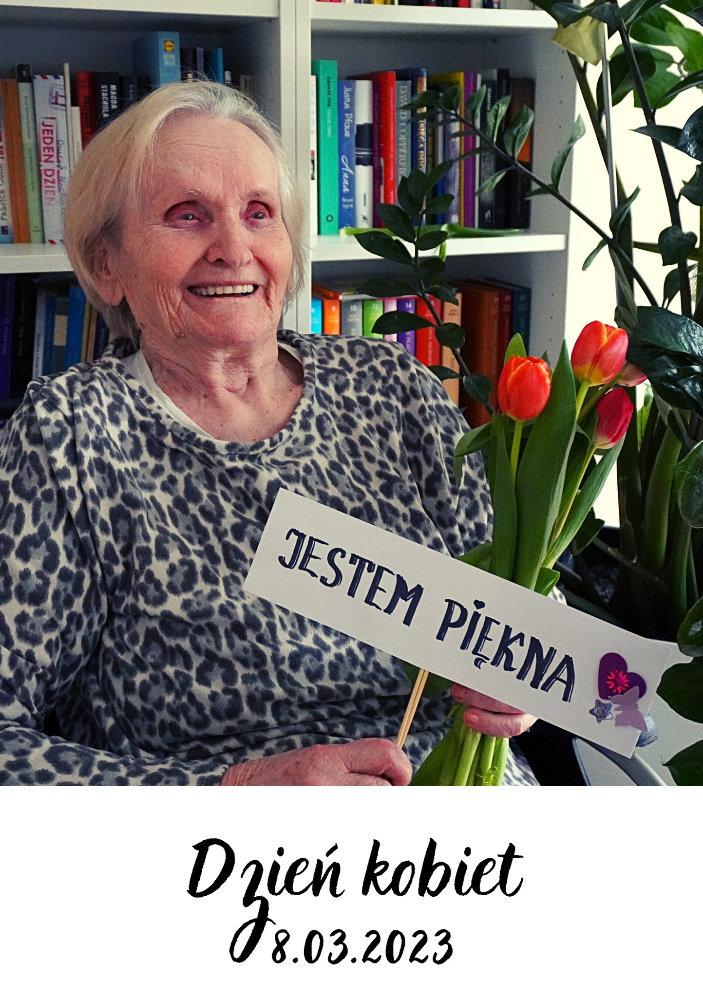 Zdjęcie starsze Pani z kwiatami, która trzyma tabliczkę z napisem "Jestem Piękna".