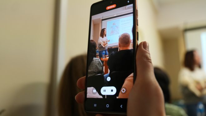 Fotografia przedstawia kadr z filmu nagrywanego smartfonem - grupę osób uczestniczących w szkoleniu Szkoły Rodzenia