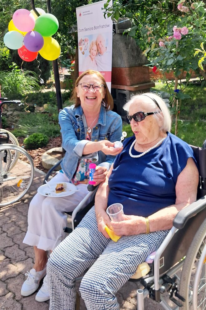Zdjęcie przedstawia dwie starsze kobiety uczestniczące w pikniku plenerowym