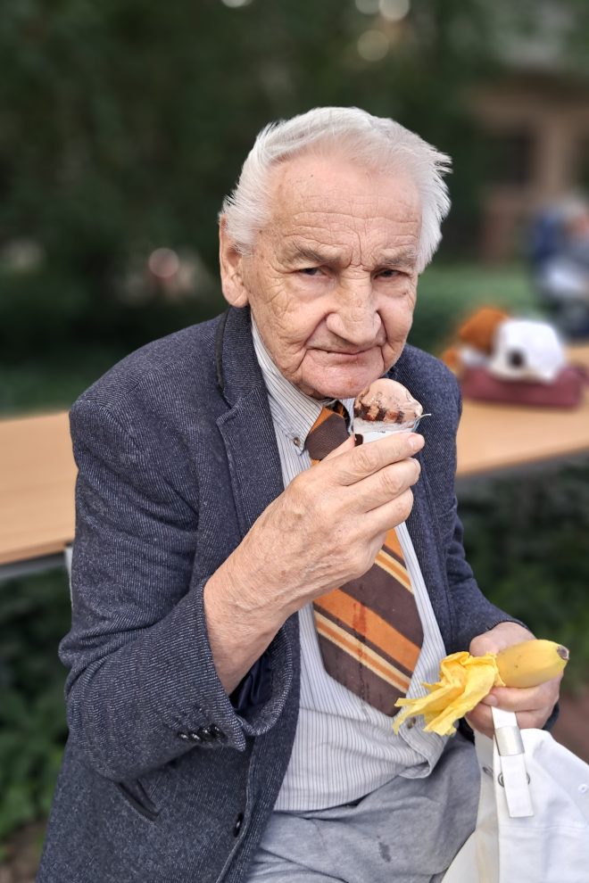 Zdjęcie przedstawia starszego mężczyznę jedzącego loda