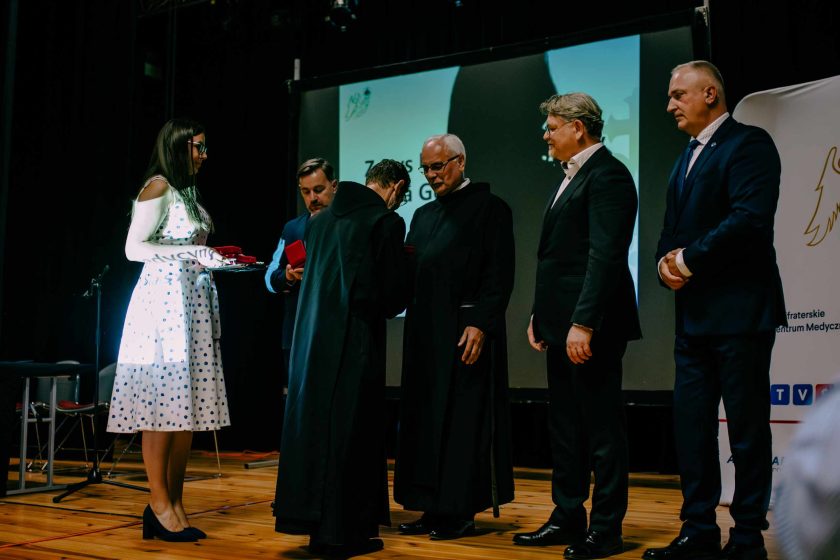 Wręczenie odznaczeń podczas uroczystości z okazji jubileuszu. Zakonnicy i świeccy otrzymują pamiątkowe medale, a całość odbywa się w uroczystej atmosferze na scenie