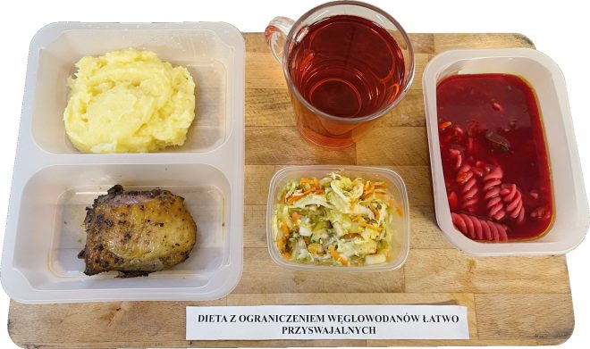 Zdjęcie pierwsze (dieta z ograniczeniem węglowodanów łatwo przyswajalnych): Taca z posiłkiem w plastikowych pojemnikach, oznaczonym jako „dieta z ograniczeniem węglowodanów łatwo przyswajalnych”. Na tacy znajdują się następujące elementy: Główne danie: pieczony kawałek mięsa z przyprawami, wyglądający na soczysty i lekko zarumieniony. Dodatek: porcja puree ziemniaczanego o kremowej konsystencji. Surówka: mieszanka świeżych warzyw, takich jak kapusta, marchewka i ogórek, drobno pokrojonych i wyglądających na soczyste. Zupa lub barszcz: czerwona ciecz w osobnym pojemniku, w którym pływają kawałki makaronu w kształcie świderków. Napój: przezroczysty kubek z czerwonym napojem, najprawdopodobniej kompotem lub herbatą owocową