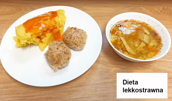 Na talerzu podano purée ziemniaczane polane pomarańczowym sosem oraz dwie niewielkie pulpety. Obok, w miseczce, znajduje się porcja zupy jarzynowej z kawałkami warzyw i przyprawami. Całość umieszczona jest na drewnianym blacie. W dolnym rogu zdjęcia znajduje się napis „Dieta lekkostrawna”