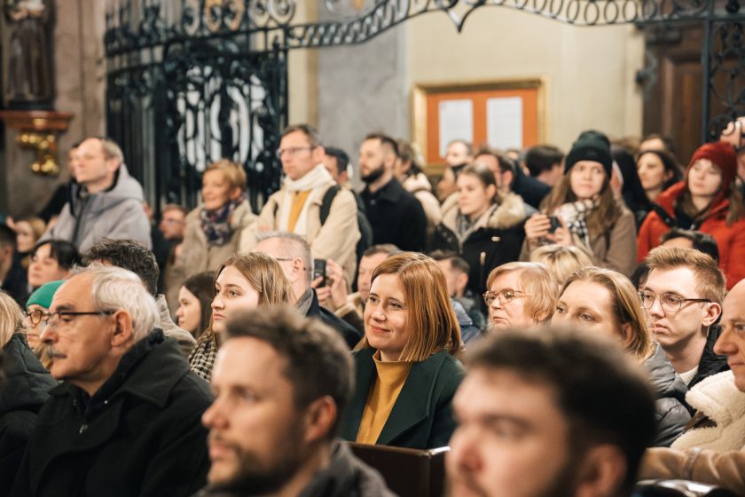 Widok na zgromadzoną publiczność, w której twarze ukazują zainteresowanie i radość. Atmosfera jest ciepła i przyjazna, podkreślając wagę wydarzenia