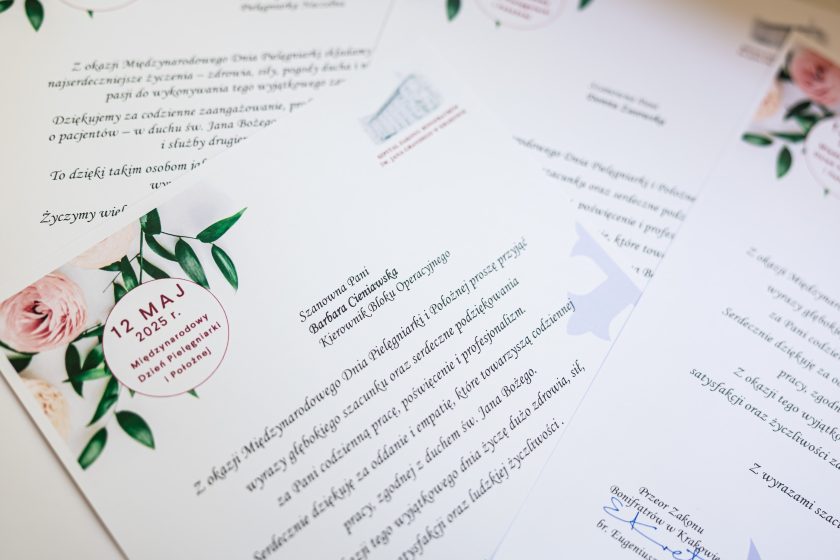 Zbliżenie na starannie przygotowane listy gratulacyjne z okazji 12 maja – Międzynarodowego Dnia Pielęgniarek i Położnych. Na pierwszym planie widoczna dedykacja dla Barbary Cieniewskiej, kierownik bloku operacyjnego. Tekst wydrukowany elegancką czcionką, ozdobiony florystycznymi grafikami i logotypami Bonifratrów. Kartki ułożone w lekkim rozchyleniu na jasnym tle, symbolicznie podkreślając liczne wyróżnienia