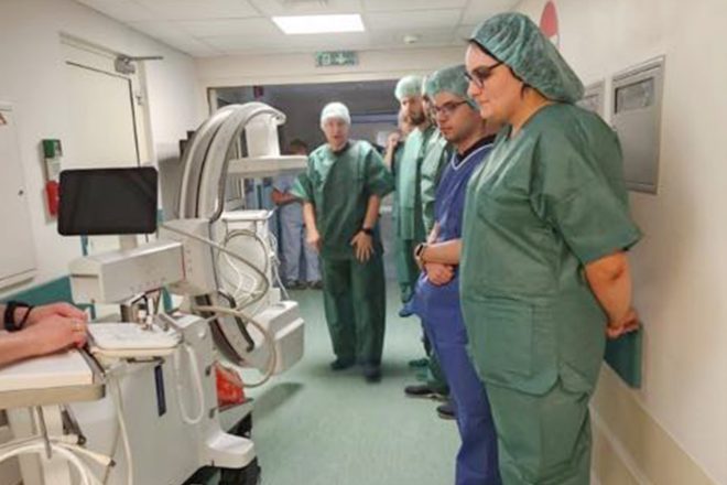 Personel medyczny uważnie obserwuje obsługę nowoczesnego aparatu diagnostycznego w szpitalnym korytarzu Bonifraterskiego Centrum Medycznego.