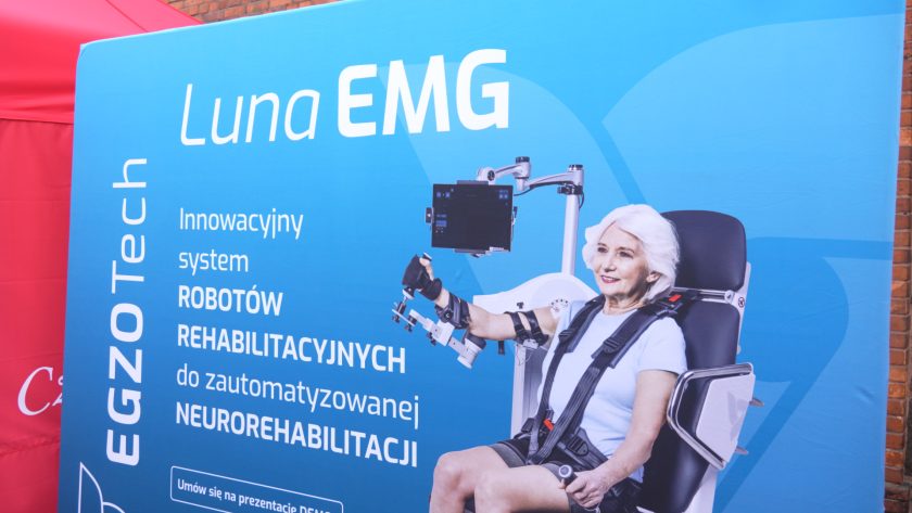 Plansza promująca system Luna EMG – robota rehabilitacyjnego do neurorehabilitacji, z wizerunkiem starszej kobiety siedzącej w specjalistycznym fotelu.