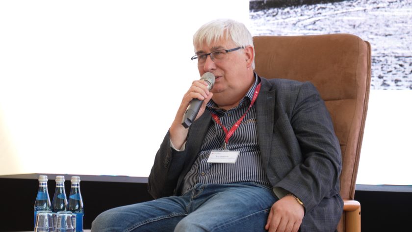 Jeden z prelegentów – mężczyzna w okularach i marynarce – dzieli się swoimi doświadczeniami z uczestnikami konferencji.