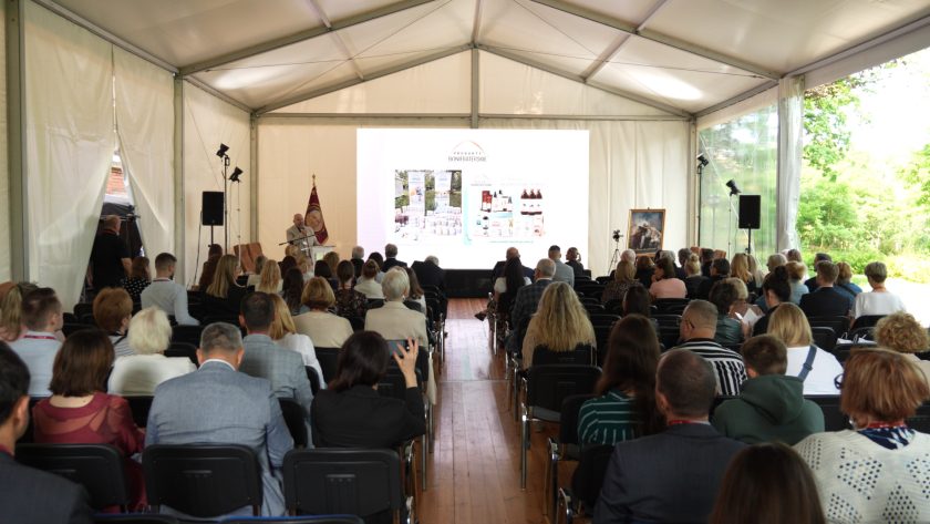 Uczestnicy konferencji oglądają prezentację dotyczącą produktów bonifraterskich. Slajd przedstawia ofertę kosmetyków i suplementów.