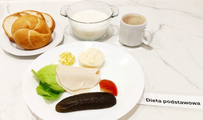 Różnorodne śniadanie: bułka i chleb, wędliny drobiowe, masło, pasta jajeczna, kiszony ogórek i warzywa (sałata, pomidor). Do tego miseczka mleka z płatkami oraz kubek kawy z mlekiem