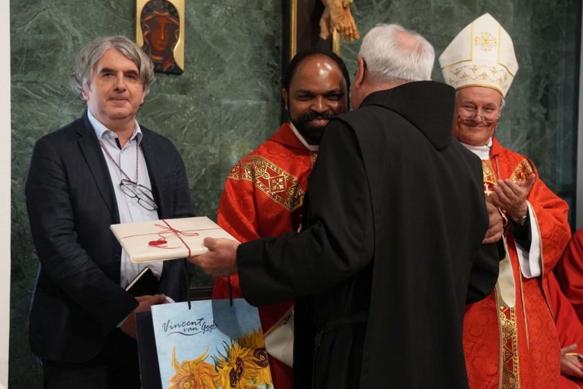 Brat Saji Mullankuzhy OH odbiera upominek od innego zakonnika podczas uroczystości w kaplicy. W tle uśmiechnięty biskup pomocniczy Michał Janocha klaszcze, a obok stoją przedstawiciele Bonifraterskiego Centrum Medycznego