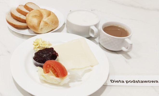 Lekkie śniadanie podstawowe: pieczywo pszenne i mieszane, plaster sera żółtego, dżem z czarnej porzeczki, masło, sałata i pomidor. Do picia kawa z mlekiem oraz mleko w kubku