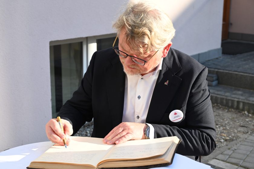 Mężczyzna w garniturze wpisuje się do księgi pamiątkowej podczas uroczystości jubileuszowych Zakonu Bonifratrów