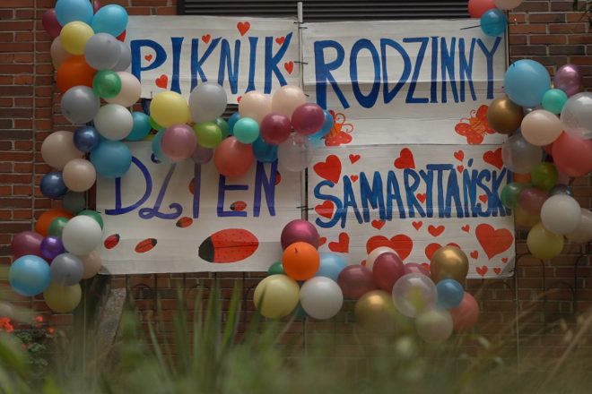 Baner pikniku – Ręcznie malowany napis „Piknik Rodzinny – Dzień Samarytański” ozdobiony balonami w wielu kolorach