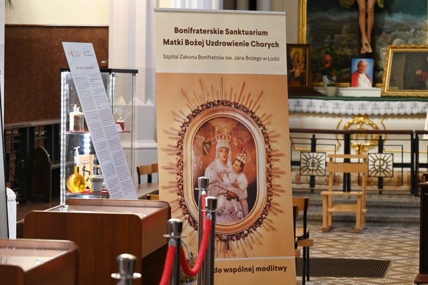 Baner przedstawiający obraz Matki Bożej z Dzieciątkiem z napisem „Bonifraterskie Sanktuarium Matki Bożej Uzdrowienie Chorych” ustawiony w kościele podczas jubileuszowej ekspozycji