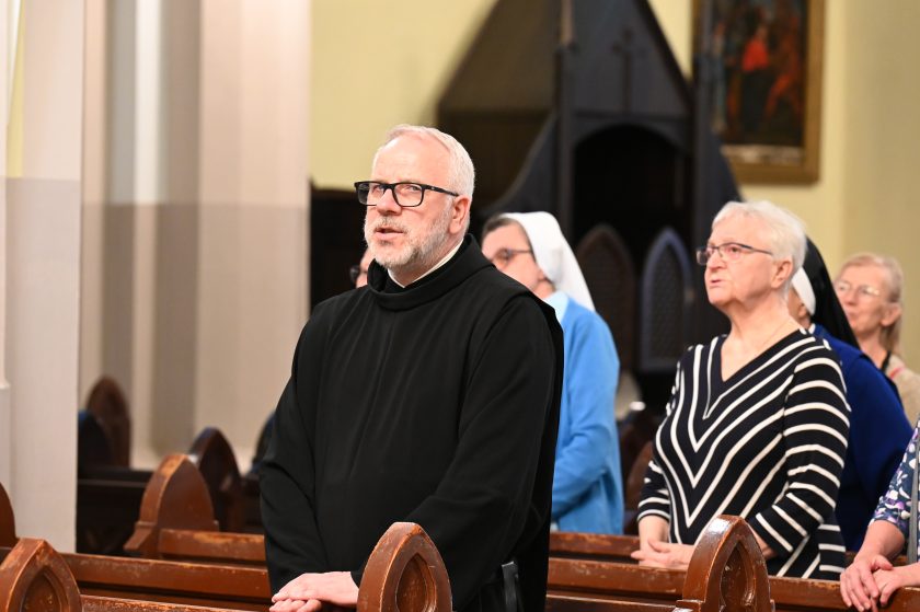 Zakonnik w habicie modli się w ławce kościelnej podczas nabożeństwa jubileuszowego
