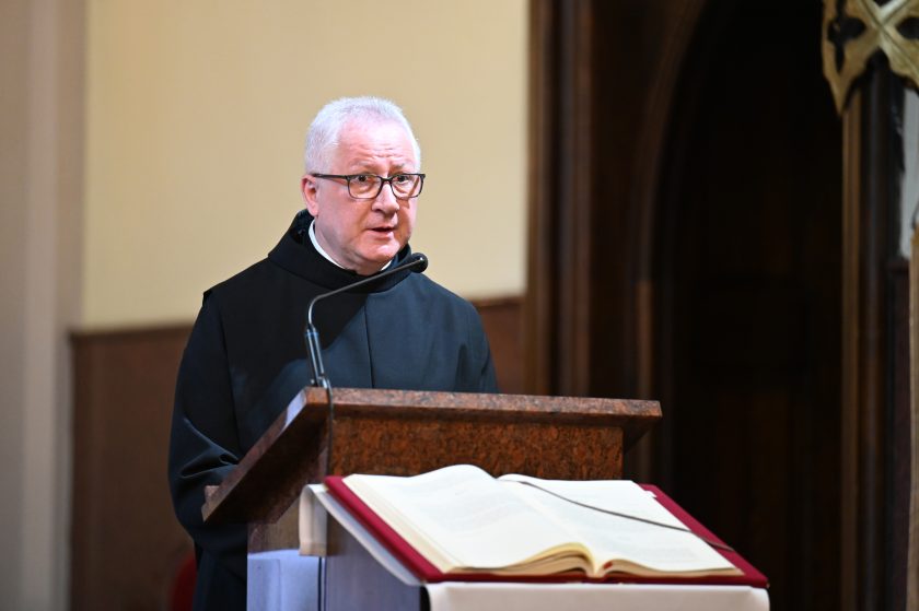 Zakonnik głosi Słowo Boże przy ambonie w kościele, obok widoczna otwarta księga liturgiczna