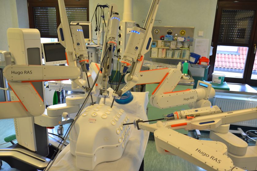 Robot chirurgiczny Hugo RAS wykonuje ćwiczenia na specjalnym trenażerze – białej kopule z otworami, służącej do treningu precyzji ruchów narzędzi