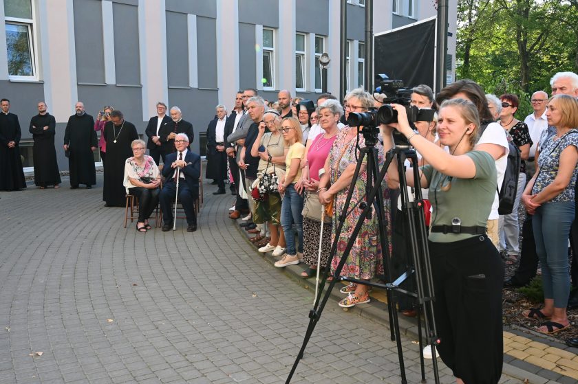 Widok na licznie zgromadzoną publiczność podczas jubileuszu Bonifratrów. Na pierwszym planie dziennikarka nagrywa wydarzenie kamerą