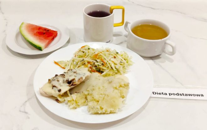 Dieta podstawowa – obiad Porcja pieczonego fileta z kurczaka pod sosem z pieczarkami, puree ziemniaczane z sosem oraz surówka z kapusty i marchwi. Do posiłku podany kawałek arbuza na osobnym talerzyku, kubek czerwonego kompotu oraz miseczka z żółtym bulionem