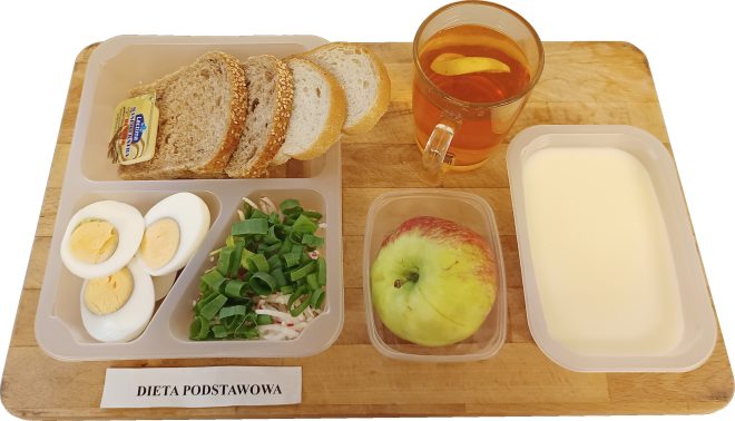 „Dieta podstawowa” Śniadanie na drewnianej tacy: trzy kromki chleba mieszanki pszenno-żytniej z sezamem, masło w opakowaniu, trzy połówki jajka na twardo, sałatka z rzodkiewki i szczypiorku, jabłko, szklanka herbaty z cytryną oraz porcja białego jogurtu w prostokątnym pojemniku