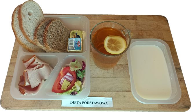 Porcja pieczywa: dwie kromki chleba pszennego i dwie kromki chleba razowego, kostka masła, plasterki wędliny drobiowej, sałatka z liścia sałaty, pomidora i czerwonej cebuli. Obok szklanka herbaty z plastrem cytryny oraz miseczka z białym jogurtem lub kefirem