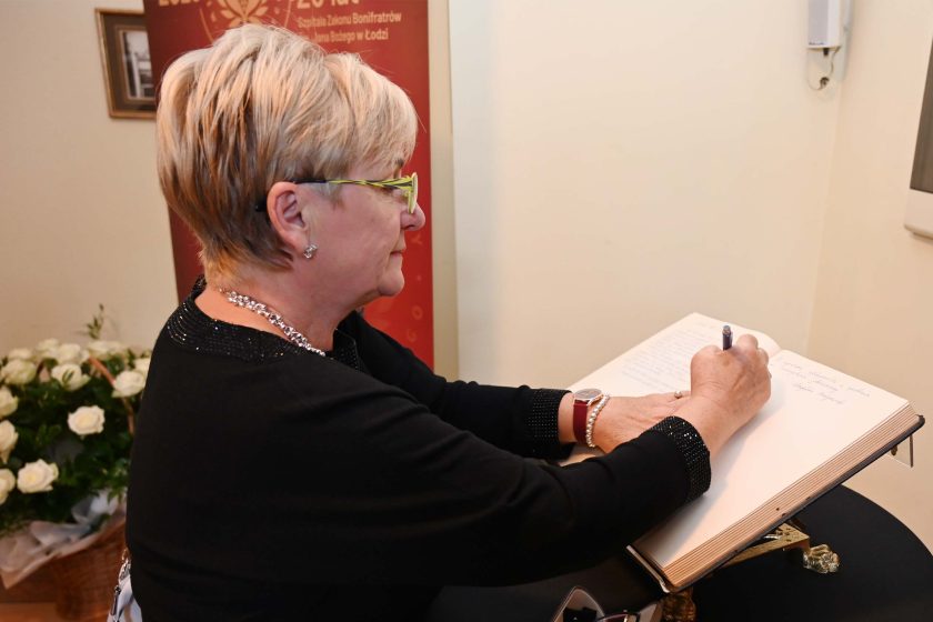 Kobieta z krótkimi blond włosami wpisuje się do księgi pamiątkowej jubileuszu. Zdjęcie 6