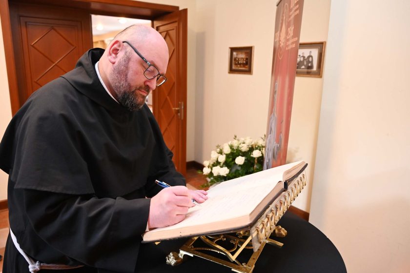 Zakonnik Bonifratrów wpisuje się do księgi pamiątkowej podczas jubileuszu w Łodzi.