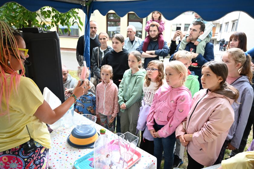 Dzieci z zaciekawieniem uczestniczą w pokazie edukacyjnym – prowadząca prezentuje im doświadczenie, a mali uczestnicy w skupieniu śledzą każdy etap