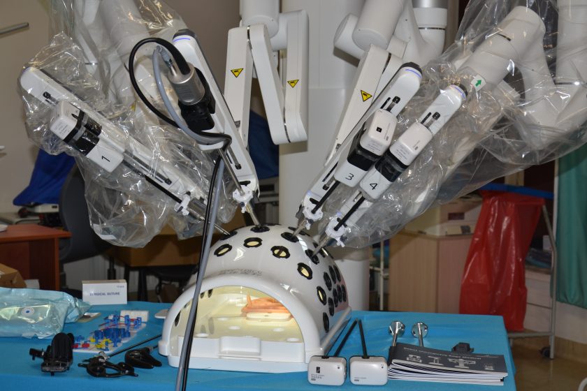 Ramiona robota chirurgicznego wykonujące zadania na modelu treningowym, na stole z akcesoriami medycznymi