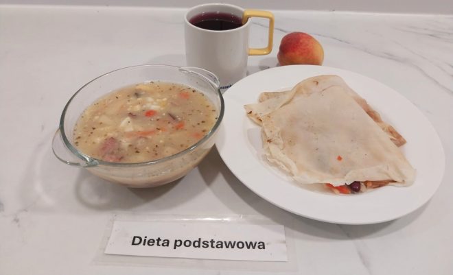 Obiad: miska z zupą jarzynową z dodatkiem mięsa i jajka, talerz z naleśnikiem nadziewanym warzywami, owoc – brzoskwinia oraz kubek z kompotem. Podpis: „Dieta podstawowa”
