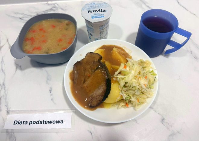 Talerz z obiadem: plaster pieczeni w sosie, ziemniaki i surówka z kapusty, obok kubek z napojem owocowym, jogurt naturalny oraz miska z zupą jarzynową. Podpis: „Dieta podstawowa”