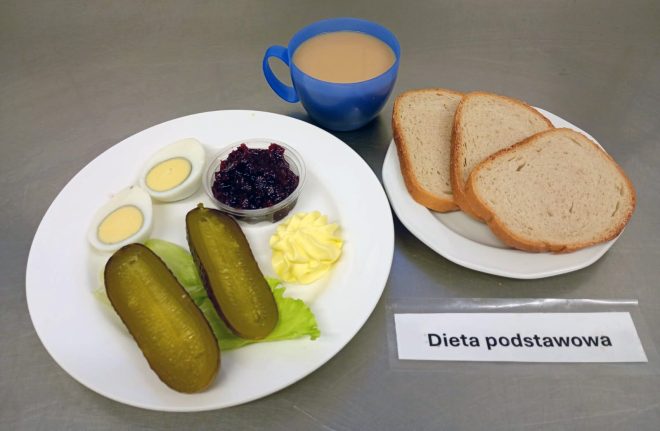Śniadanie w diecie podstawowej: jajko na twardo, ogórek kiszony, konfitura owocowa, porcja masła, kromki chleba pszennego i kubek kawy z mlekiem