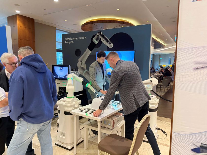 Uczestnicy Kongresu obserwują pokaz nowoczesnych robotów chirurgicznych wykorzystywanych w zabiegach małoinwazyjnych. Stoisko prezentacyjne z robotami i ekranami demonstracyjnymi