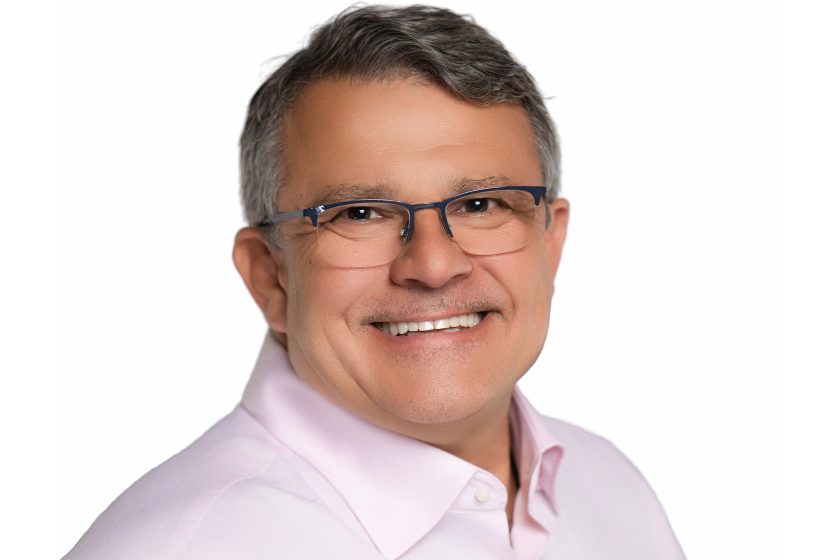 Portret mężczyzny w różowej koszuli i okularach, uśmiechniętego, na białym tle. Zdjęcie studyjne, przedstawiające osobę w profesjonalny, przyjazny sposób