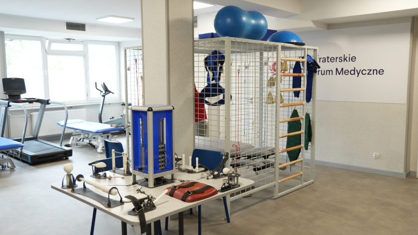 Nowoczesna sala rehabilitacyjna w Bonifraterskim Centrum Medycznym. Widać bieżnię, stoły do ćwiczeń, klatkę UGUL z przyrządami i piłkami gimnastycznymi
