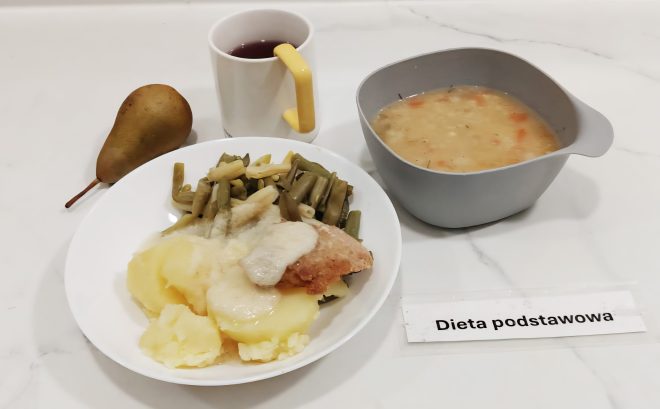 Zestaw obiadowy w diecie podstawowej: ziemniaki z zieloną fasolką szparagową, panierowany filet z sosem, zupa jarzynowa w misce, kubek z herbatą owocową i gruszka jako deser