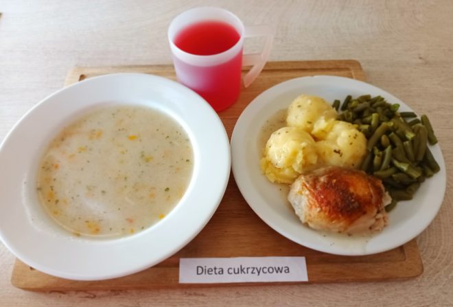 Obiad w diecie cukrzycowej: zupa jarzynowa, ziemniaki, gotowana fasolka szparagowa, pieczony kawałek kurczaka oraz kompot owocowy. Posiłek podany na białych talerzach
