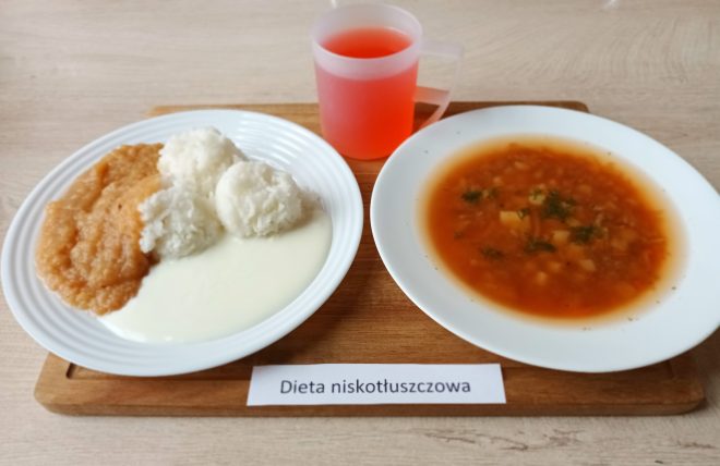 Zestaw obiadowy w diecie niskotłuszczowej: talerz z ryżem, musem jabłkowym i jogurtem naturalnym; obok talerz z klarowną zupą jarzynową oraz kubek czerwonego napoju