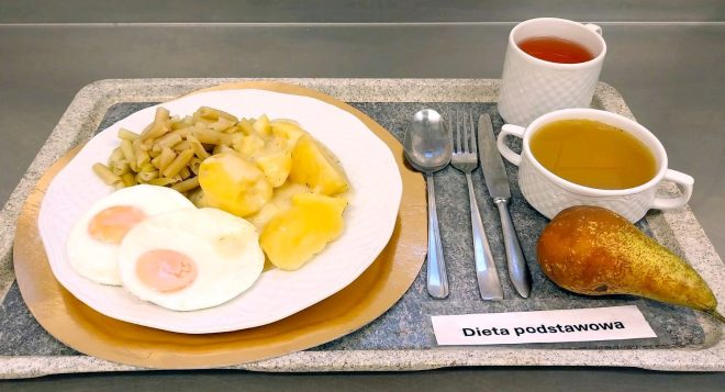 Zestaw obiadowy na diecie podstawowej: dwa jajka sadzone, gotowane ziemniaki z koperkiem, fasolka szparagowa, zupa i herbata; obok leży gruszka