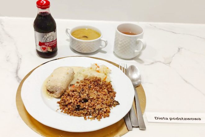 Zestaw obiadowy na diecie podstawowej: gotowany kurczak w sosie, kasza gryczana z warzywami i kapustą kiszoną; zupa jarzynowa i herbata, obok butelka soku z buraka