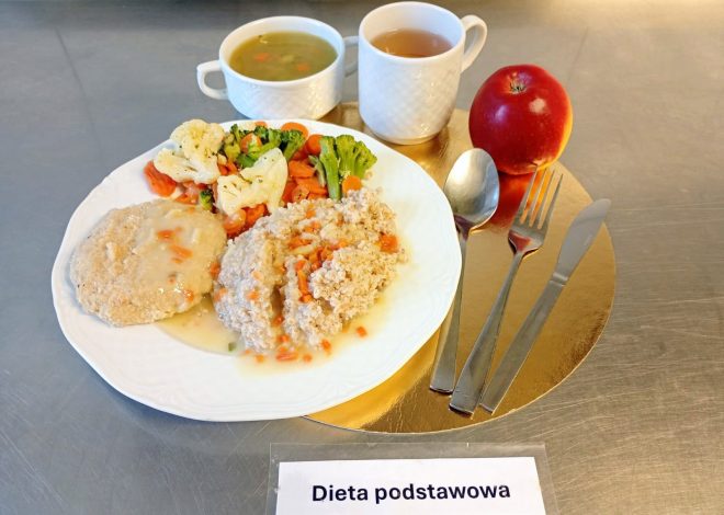 Zestaw obiadowy w diecie podstawowej: na talerzu kasza jęczmienna z warzywami, kotlet mielony w jasnym sosie oraz porcja gotowanych warzyw — marchewki, brokuła i kalafiora. W tle dwa białe kubki: jeden z zupą jarzynową, drugi z herbatą. Obok leży czerwone jabłko i komplet sztućców. Całość ustawiona na złotej podkładce z podpisem „Dieta podstawowa”