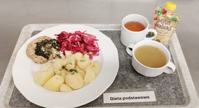 Zestaw obiadowy w diecie podstawowej: gotowane ziemniaki z koperkiem, kotlet z warzywną zapiekanką ze szpinakiem, surówka z czerwonej kapusty. Do posiłku podano zupę, herbatę oraz owocowy mus w saszetce.