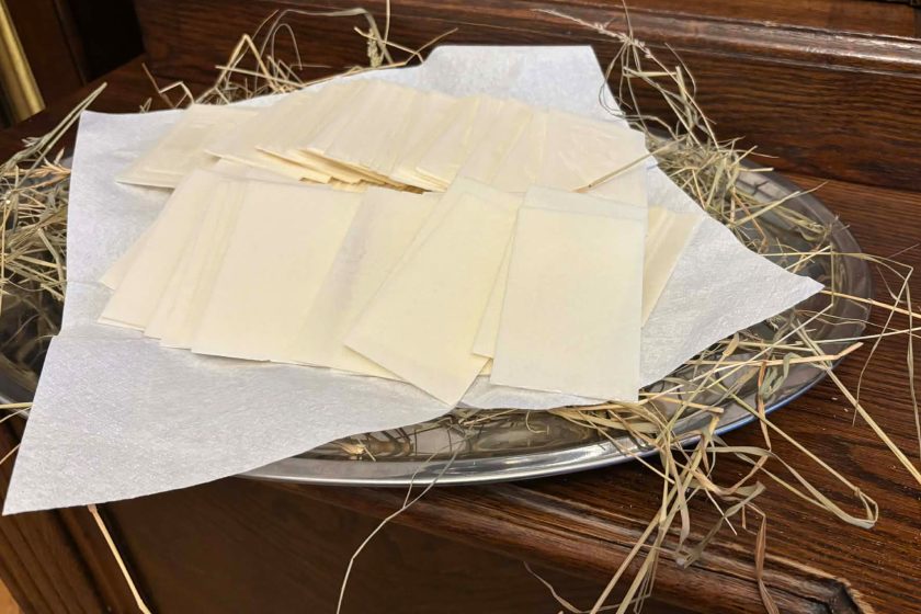 Opłatki ułożone na półmisku wyłożonym sianem, przygotowane do tradycyjnego dzielenia się podczas spotkania opłatkowego