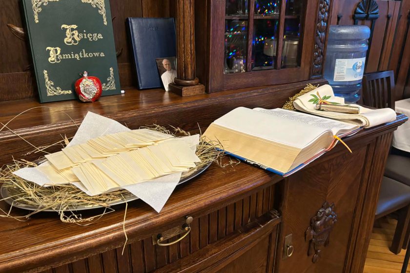 Stół z opłatkami, otwartą księgą oraz świątecznymi dekoracjami, przygotowany na spotkanie opłatkowe