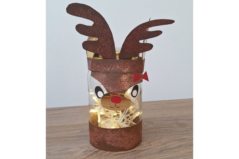 Szklany lampion w formie renifera z brokatowymi rogami i czerwonym nosem, wypełniony światełkami LED