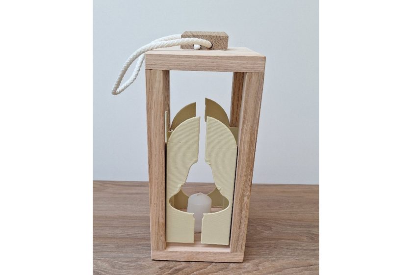 Drewniany lampion z prostą ramą i uchwytem ze sznurka, wewnątrz świeczka osłonięta jasnymi dekoracyjnymi elementami
