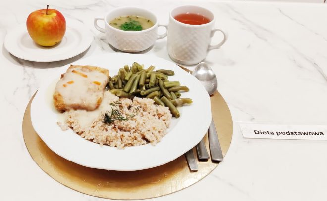 Obiad w diecie podstawowej: filet rybny w sosie, kasza, fasolka szparagowa oraz zupa i napój, podane na zastawie stołowej