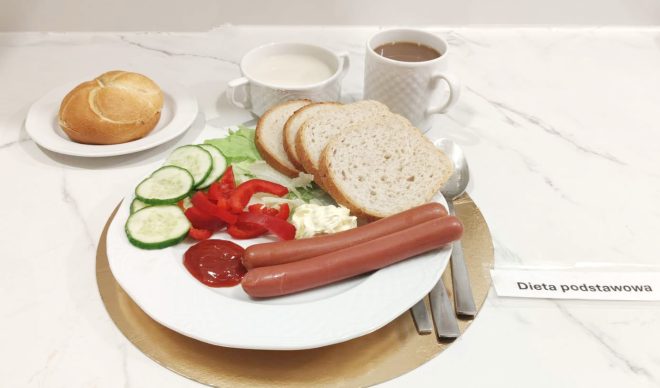 Śniadanie na diecie podstawowej: parówki, pieczywo pszenne, warzywa, masło i ketchup, napój mleczny oraz kawa zbożowa